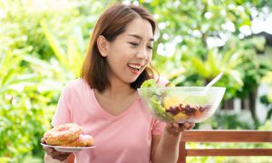 woman looking at healthy food over donuts